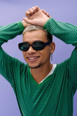 Saçları boyalı genç bir Afro-Amerikalı mor bir elbiseyle rahatça poz veriyor..