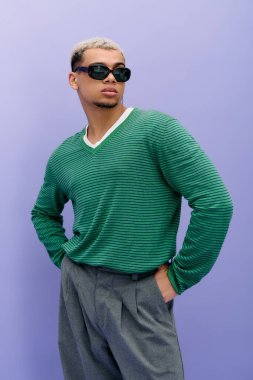 Saçları boyalı şık bir genç adam mor bir arka plan önünde kendinden emin bir şekilde poz verir..