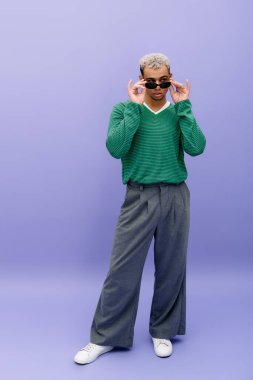 Boyalı saçlı genç bir siyahi, özgün tarzını mor bir fonda gururla sergiliyor..