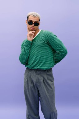 Kendine güvenen genç bir zenci şık bir şekilde poz veriyor. Saçları boyalı ve şık bir kıyafeti var..