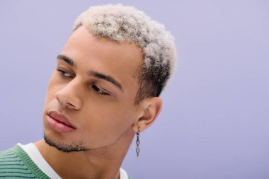 Saçları boyalı, Afro-Amerikalı genç bir adam şık bir kıyafetle rahatça poz veriyor..