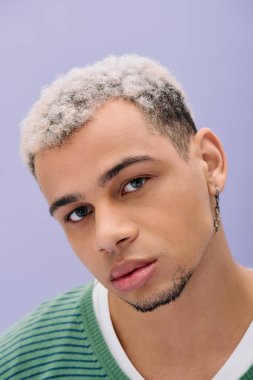 Genç Afrikalı Amerikalı bir adam gururla modaya uygun bir şekilde poz veriyor. Saçları yaratıcı bir şekilde boyanmış..