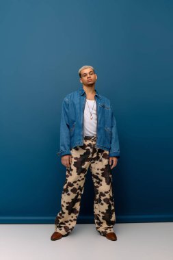 Genç bir Afro-Amerikan erkeği, saçları boyalı, kendine güvenen bir kot ceketle poz veriyor..