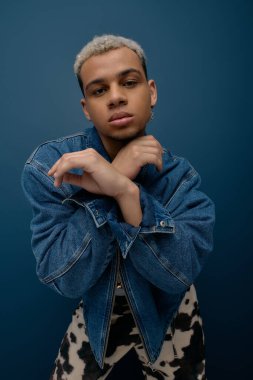 Kendine güvenen genç bir Afrikalı Amerikalı kot ceketli çapraz kollu poz veriyor..