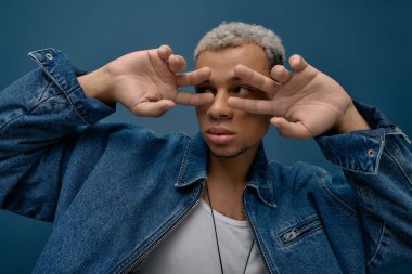 Genç bir Afrikalı Amerikalı erkek, kendine güvenen bir kot ceketle poz veriyor..