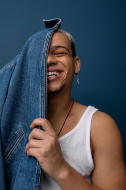 Genç siyahi bir adam kot ceketiyle neşeli pozlar veriyor, tarzını ve boyalı saçlarını gösteriyor..