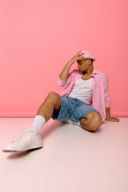 Genç siyah bir adam pembe bereli bir şekilde poz veriyor..