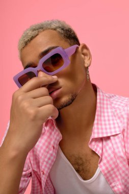 Modayı takip eden genç bir adam parlak saç ve güneş gözlüğü takıyor..