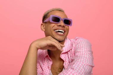 Genç bir Afrikalı Amerikalı moda anlayışını damalı gömlek ve güneş gözlükleriyle gösteriyor..
