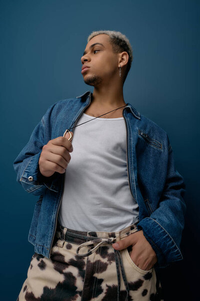A young African American man flaunts his stylish denim jacket while striking a confident pose.