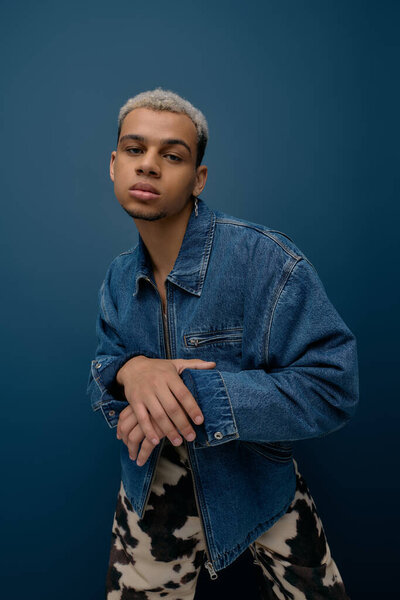 A young african american man with dyed hair poses confidently in a fashionable denim jacket.