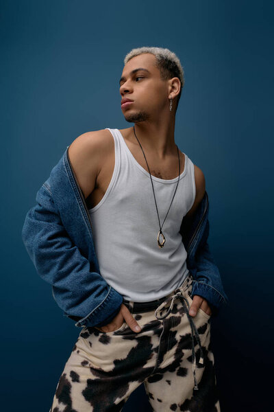 A confident young man with dyed hair poses in a fashionable denim jacket, highlighting modern style.