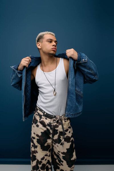 Confident young man with dyed hair poses in a trendy denim jacket, exuding style and charisma.