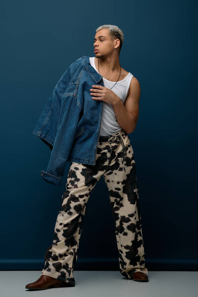 A young african american man showcases a trendy outfit featuring a denim jacket.