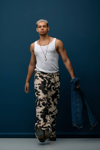A young African American man with dyed hair poses confidently in a trendy denim jacket.