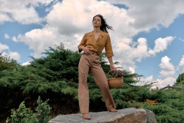 Kendine güvenen genç kadın, yemyeşil bir sepetle şık bir yaz kıyafeti sergiliyor..