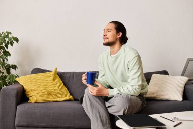 Rahat genç bir adam rahat bir kanepede oturur, hayatın tadını çıkarırken..