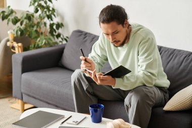 Yakışıklı genç adam rahat bir kanepede oturuyor, defterine yazdığı gibi derin düşüncelere dalmış..