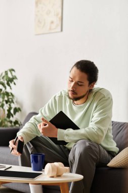 Düşünceli bir genç adam, davetkar yaşam alanında rahatça otururken fikirleri düşünüyor..