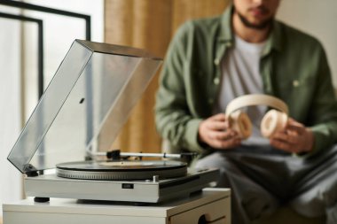 Yakışıklı bir genç adam sıcak, davetkar bir atmosferde kulaklıklarla evde dinleniyor..