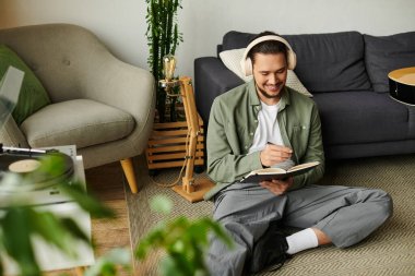 Odaklanmış bir insan yerde oturur, rahat bir evde kulaklıkla yazar..