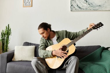 Evdeki yakışıklı genç adam bir kanepede oturur, gitar çalar ve sessiz bir anın tadını çıkarır..