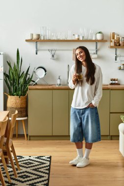 Genç bir kadın evinde rahatlıyor, içkisini yudumluyor ve rahat bir atmosferi kucaklıyor..