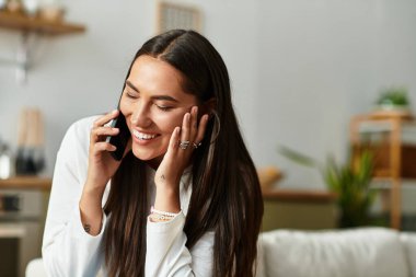 Parlak ve neşeli genç bir kadın evinde rahat bir ortamda neşeli bir sohbetten hoşlanıyor..