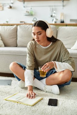 Evde dinlenen genç bir kadın, elinde müzik ve içkiyle günlüğünü yazıyor..