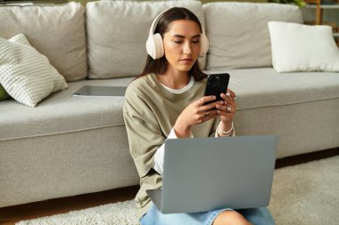 Genç bir kadın evde kulaklık takarak rahatlıyor ve cep telefonuyla meşgul oluyor..