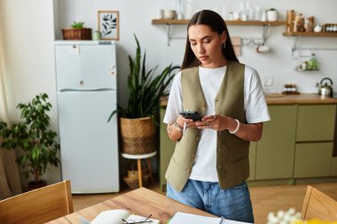 Güzel bir kadın şık bir mutfakta duruyor, telefonuyla meşgul..