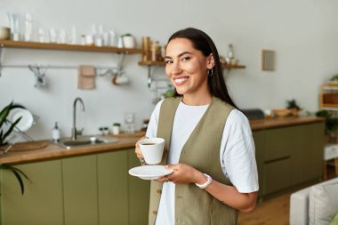 Parlak ve davetkar bir yer. Bir kadın evinde neşeli bir enerjiyle içkisinin tadını çıkarıyor..