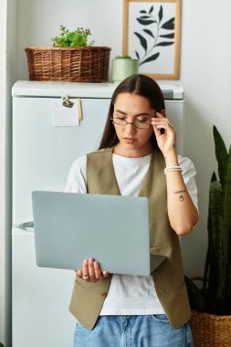 Güzel genç bir kadın sıcak ve davetkar bir atmosferde dizüstü bilgisayarına odaklanıyor..