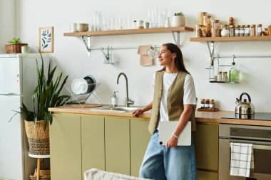 Güzel genç bayan modern mutfağında rahatlıyor, evinin rahatlığının tadını çıkarıyor..