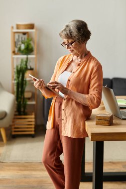 Kıdemli kadın sıcak ve davetkar bir yaşam alanında tabletine sarılıyor..