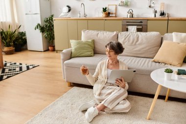 Son sınıf bir kadının tablet kullanırken içkisini yudumladığı samimi bir sahne..
