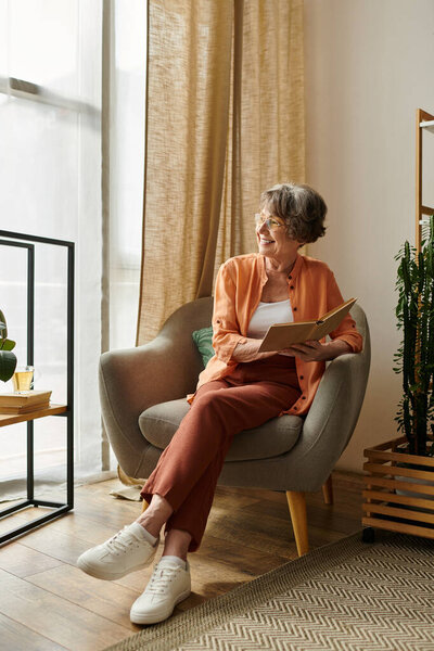 A mature woman in comfy attire savors a good book while relaxing in her cozy living space.
