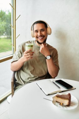 Sakallı genç adam bir kafede mutlu bir şekilde Matcha yudumluyor.