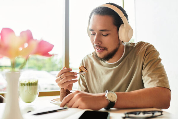 A young man with a beard savoring matcha and cake.