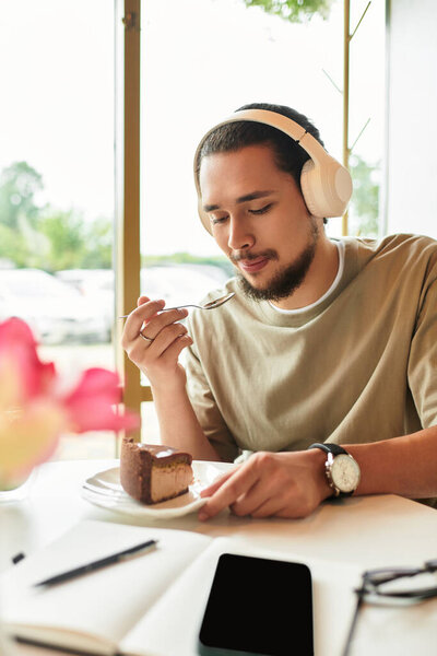 Young man indulges in cake and matcha while relaxing in cafe setting.