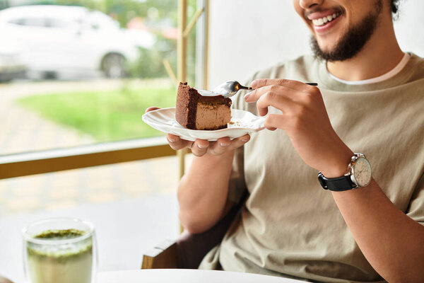 Young man enjoys cake and matcha in a cozy cafe.