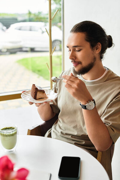 Young man enjoys cake and matcha in a bright cafe during summer.
