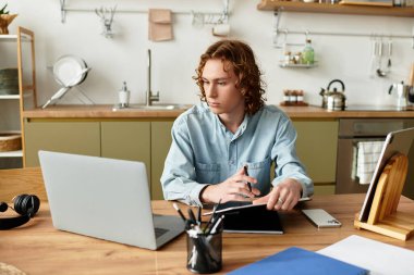 Genç adam, sıcaklıkla çevrili şık bir mutfak masasındaki görevlerine odaklanıyor..