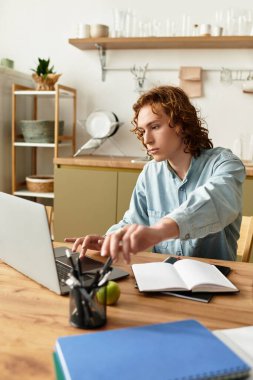 Yakışıklı genç adam, doğal ışıkla dolu modern bir ev ofisinde aktif olarak ders çalışıyor..