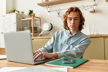 Yakışıklı genç adam ahşap bir masada oturuyor, dizüstü bilgisayarında daktilo yazarken sade titreşimleri emiyor..