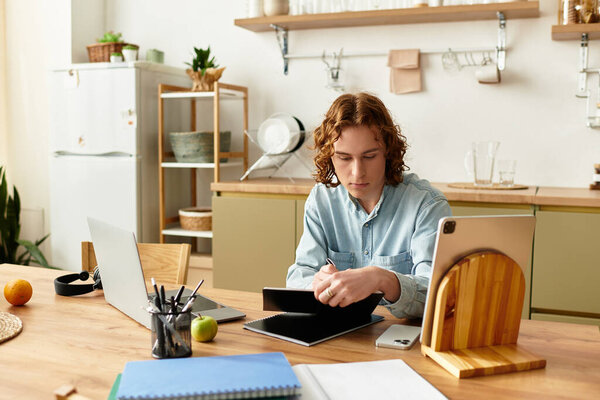 A young man is focused on his tablet in a cozy, modern home office.
