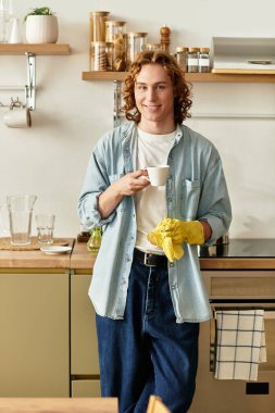 Genç ve yakışıklı bir adam şık mutfağında durur, kahvesini yudumlar ve kendini evinde hisseder..