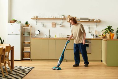 Yakışıklı genç bir adam modern mutfağını temizliyor. Üretken bir öğleden sonra rutinine dalmış..