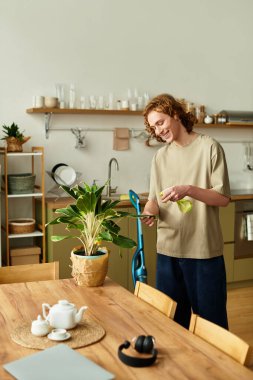 Gülümseyen bir insan sıcak, rahat bir mutfakta yapraklı bir bitkiyi önemser..