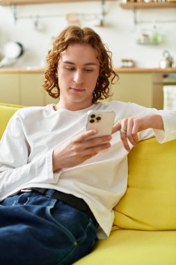 Yakışıklı bir genç adam güneşli bir öğleden sonra akıllı telefonuyla rahatça uzanır..